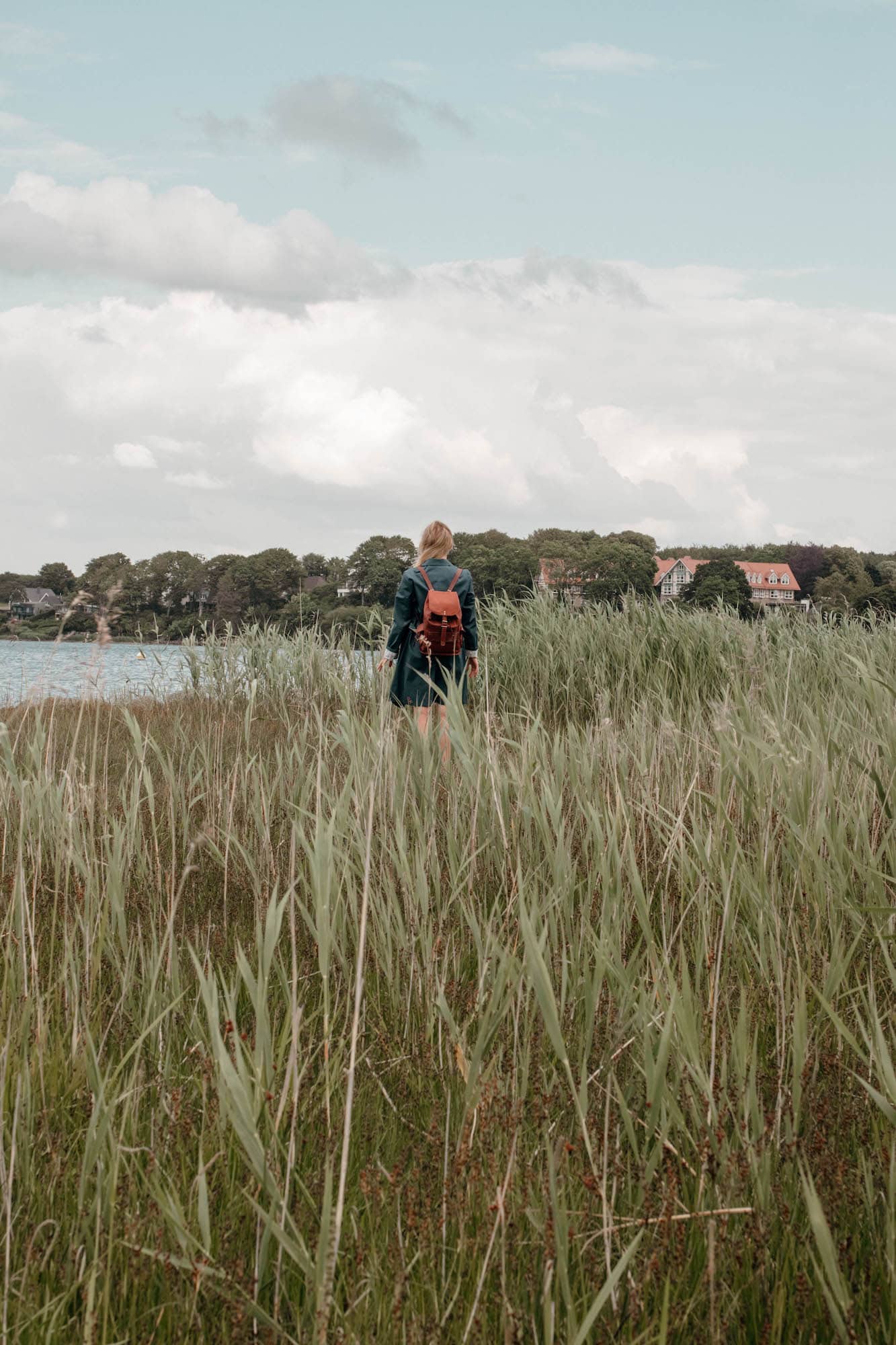 frau mit rucksack am wasser flensburger förde